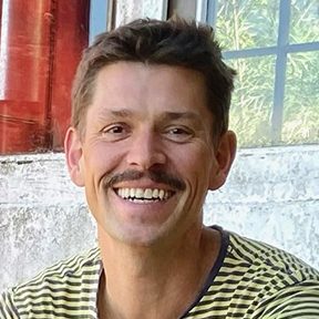 Portrait of Steffen Kreft, illustrator and mural artist, smiling outdoors.